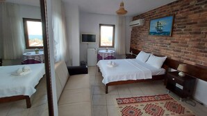 Una habitación de hotel con una cama, una mesita con una planta, un televisor y un ventanal con cortinas.