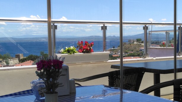 Una mesa con vistas al mar y a las montañas a través de amplios ventanales.