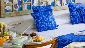 A dining area with a table set for breakfast, including plates of food, cups, and a vase of flowers. - Pousada Solar Dos Deuses (Salvador)