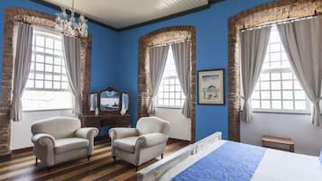 A room with a bed, two armchairs, a wooden bench, and a dresser.