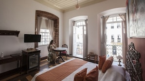 A hotel room with a bed, a television, a desk, and a balcony with a view of buildings. - Pousada Solar Dos Deuses (Salvador)