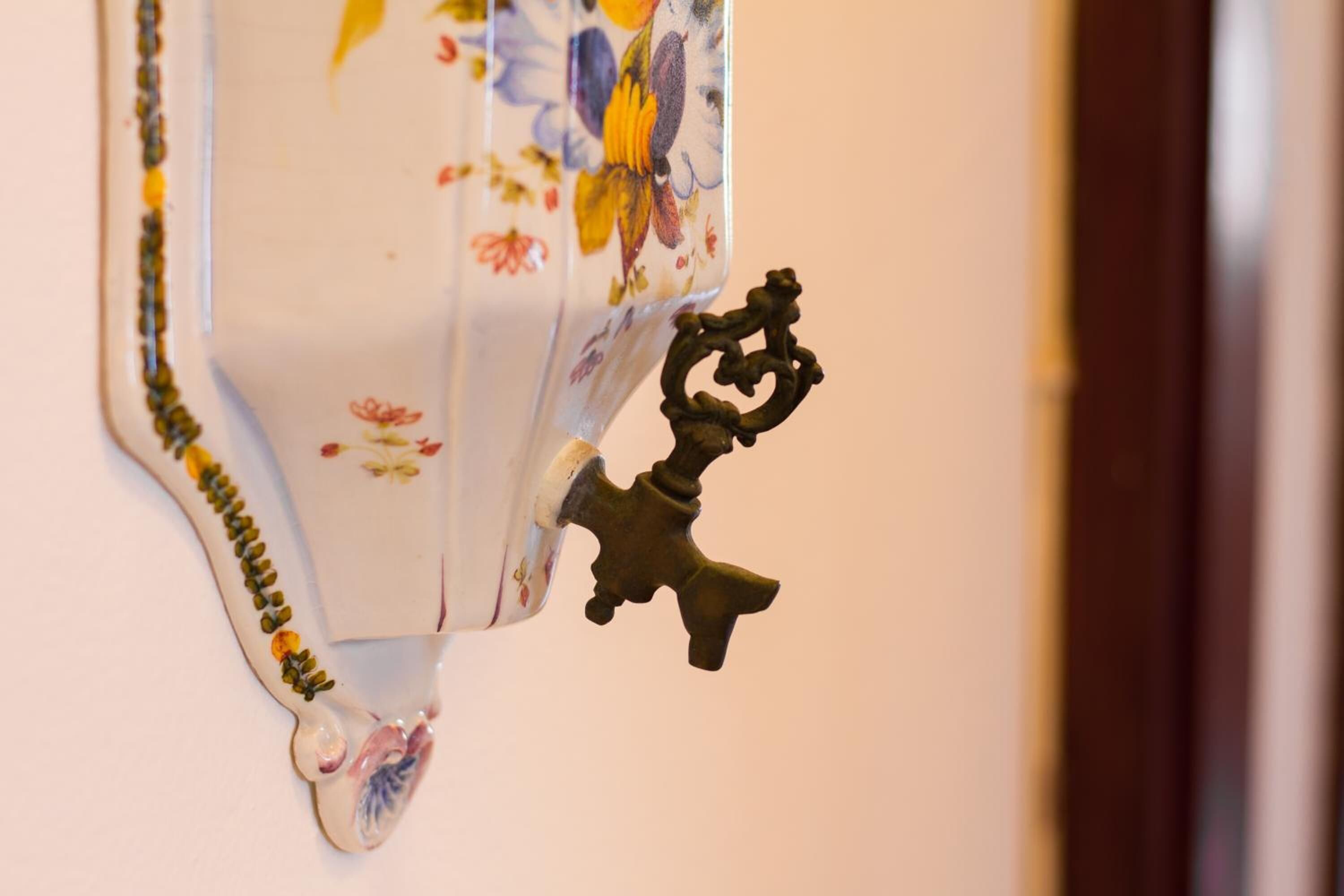 Un objeto decorativo para colgar en la pared con estampado floral y un detalle que recuerda a una llave de metal.