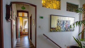A hallway with striped flooring, a staircase, and a painting on the wall. - Pousada Solar Dos Deuses (Salvador)