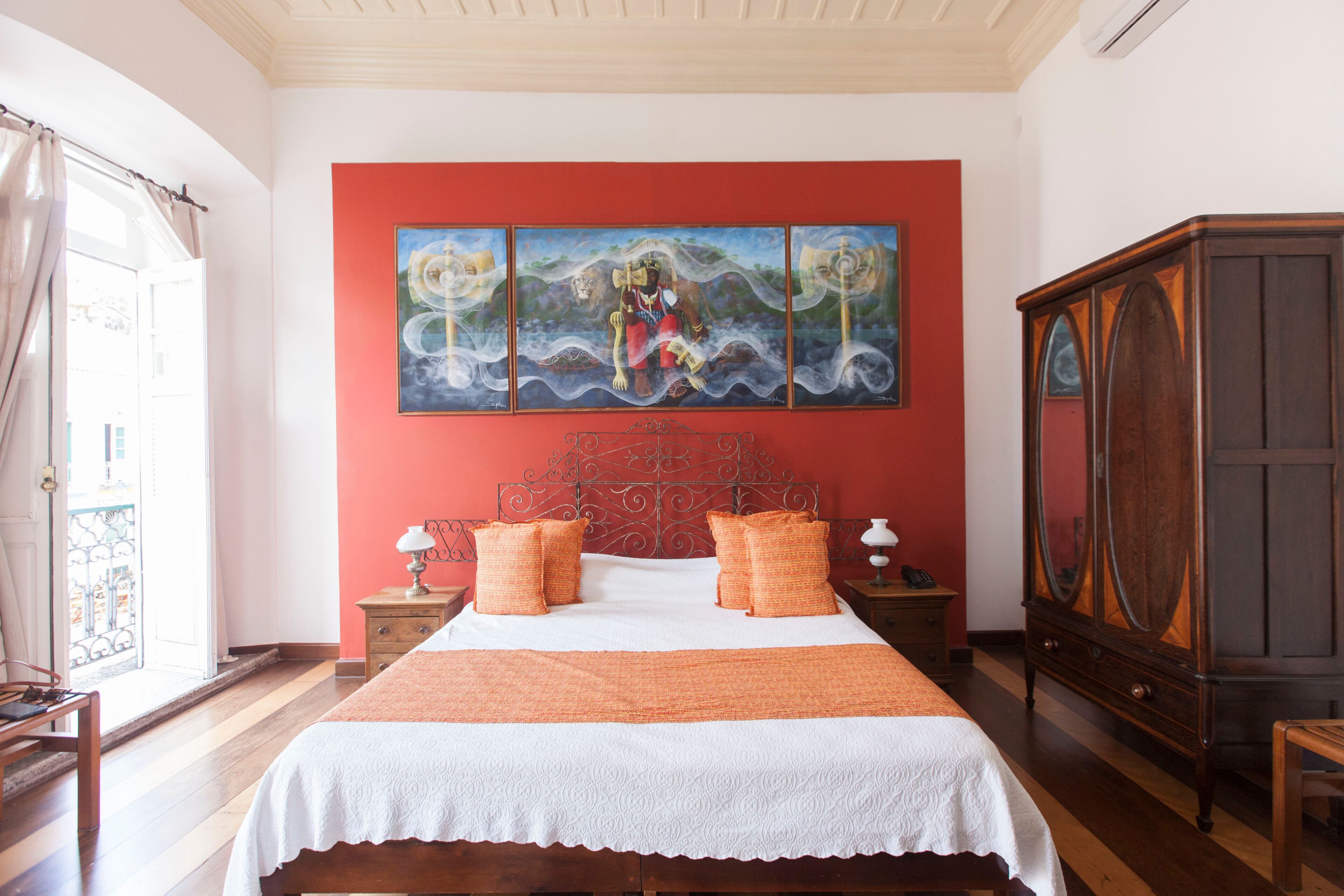 A bedroom with a bed, a nightstand, a dresser, and a painting on the wall.