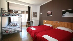 Habitación de hotel con literas, dos camas individuales, un escritorio y una silla.