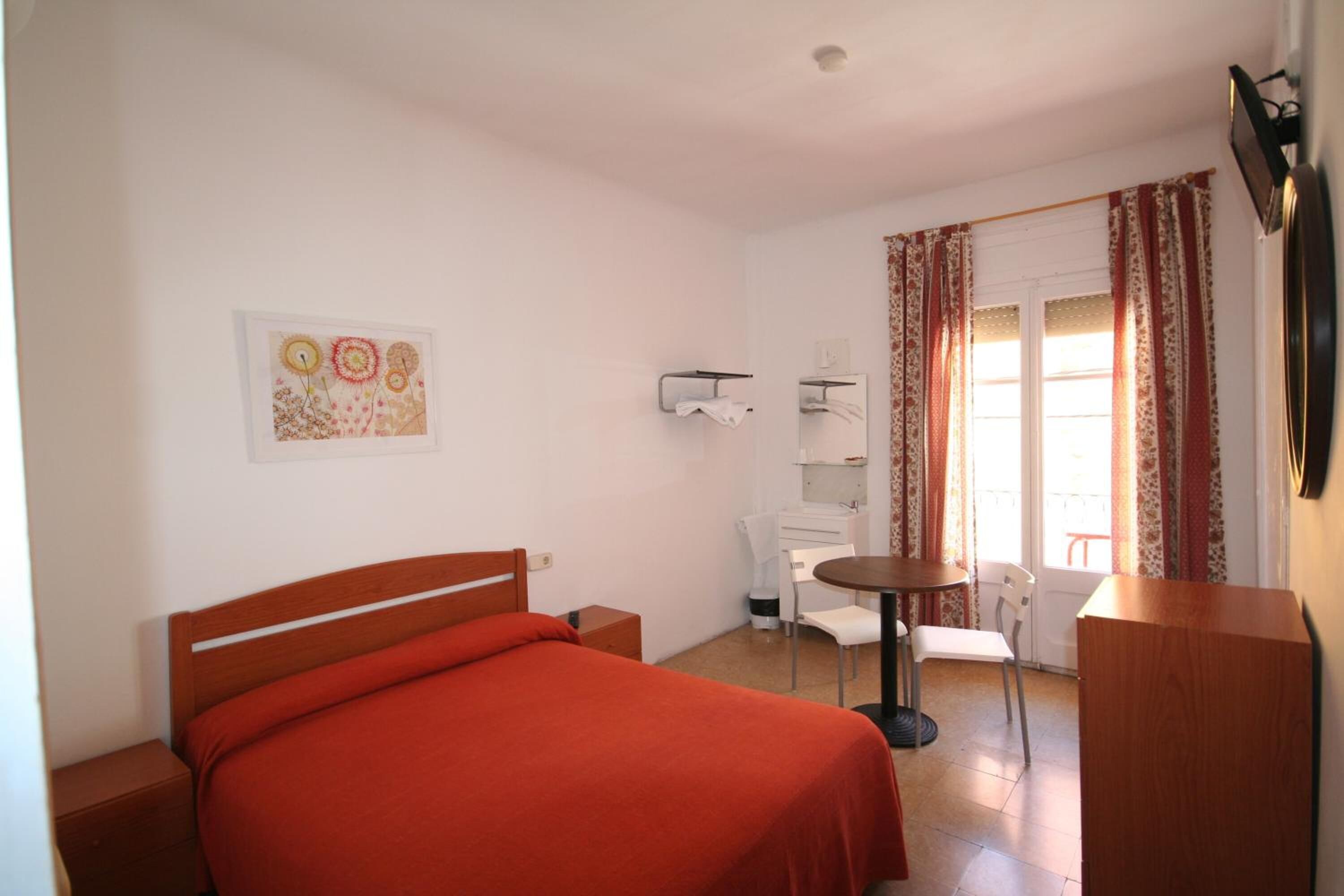 Quarto com cama, escrivaninha, cadeira e mesinha.
