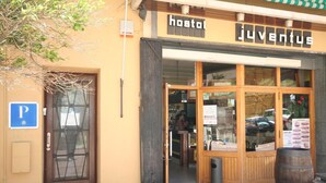 Un hostal con fachada de madera y un amplio ventanal que muestra diferentes objetos.