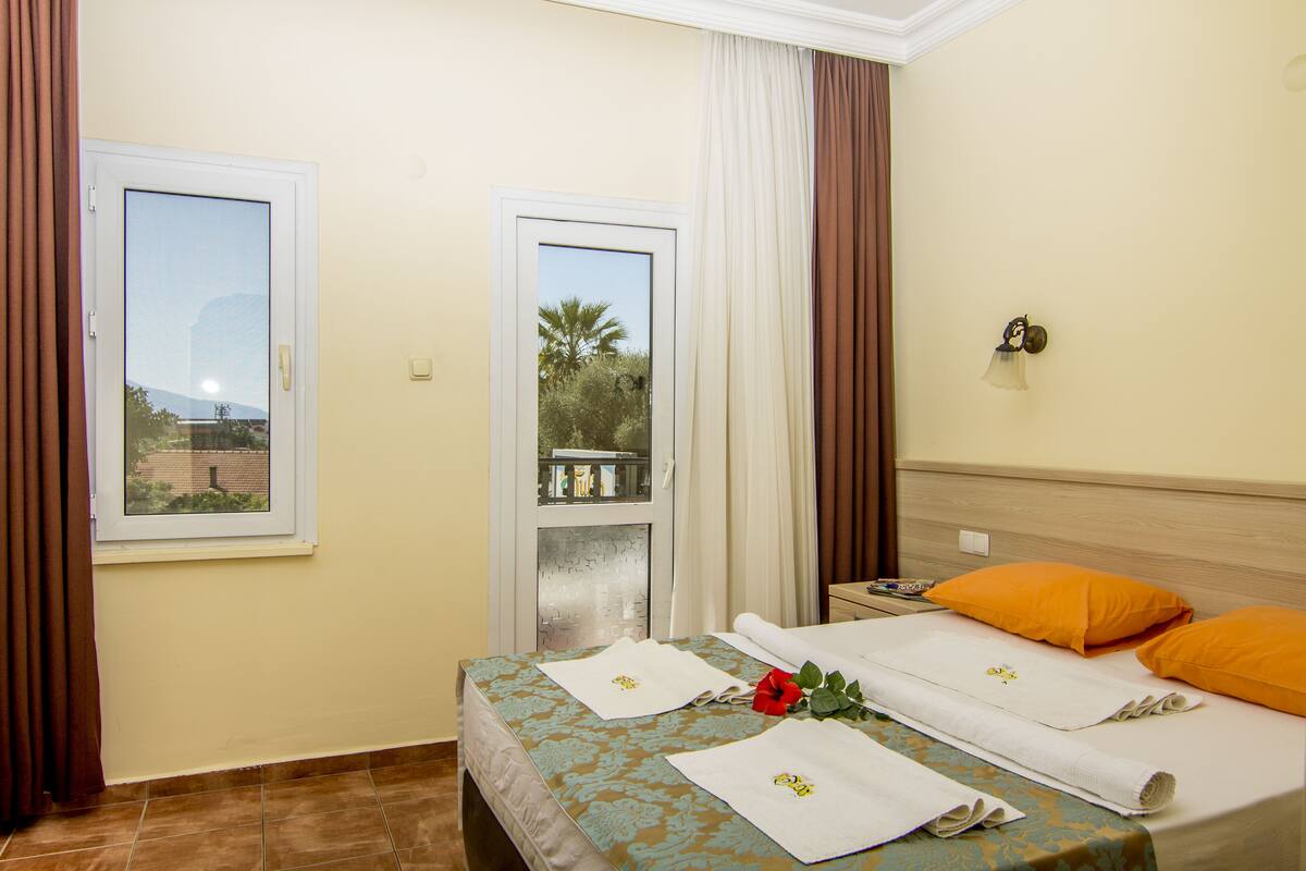 A hotel room with a bed, a window, curtains, and a view of palm trees.