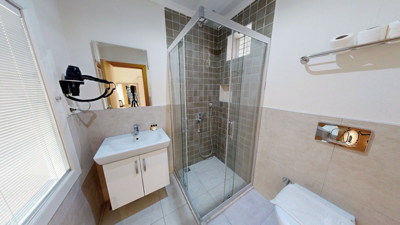 Een badkamer met een douchecabine van glas, een wastafel met kastjes en een handdoekrek.
