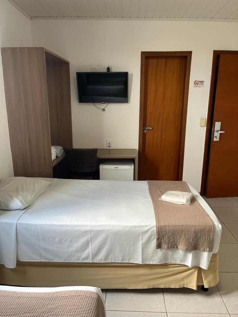 A hotel room with a bed, a desk, a television, and a wardrobe.