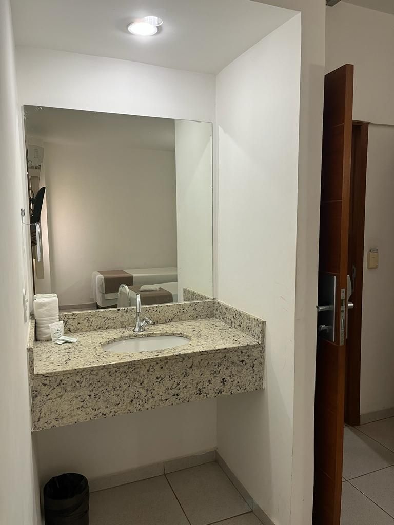 A bathroom with a granite countertop sink, a mirror above it, and a door to a shower area.