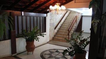 Un vaste espace intérieur agrémenté d’un escalier, de plantes en pot et d’un motif décoratif sur le sol.