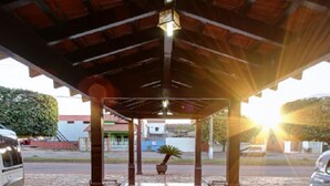 A covered outdoor area with tiled flooring, columns, and a potted plant.