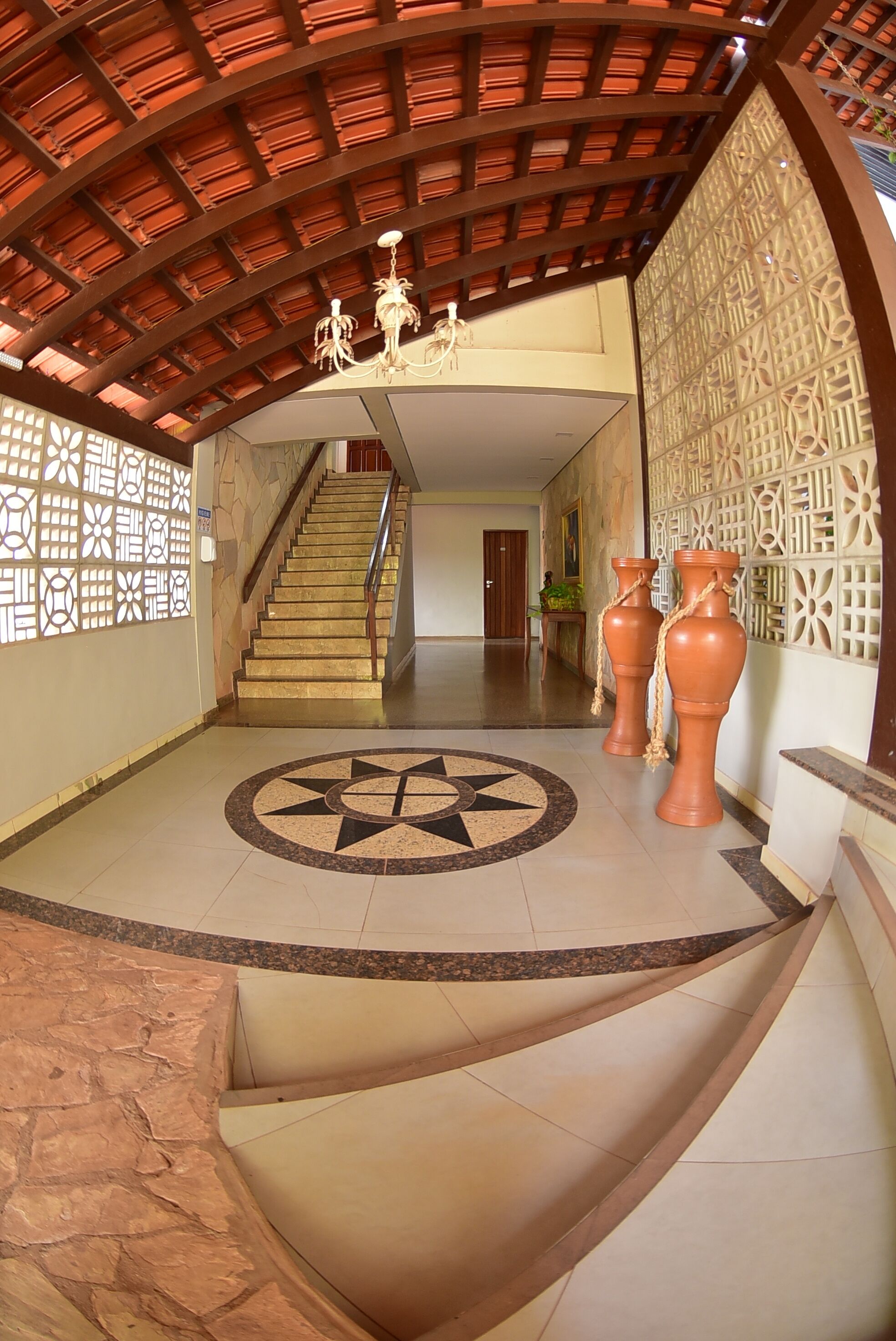 Un hallo amplio con una escalera central, jarrones decorativos y paredes con diseño.