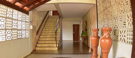 A spacious lobby with a central staircase, decorative vases, and patterned walls.
