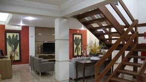 A modern living room with a wooden staircase, a television, and a sofa.