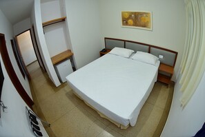 A hotel room with a large bed, a nightstand, a wooden shelf, and a wall-mounted artwork. - Ecos Hotel Tourist (Rolim de Moura)
