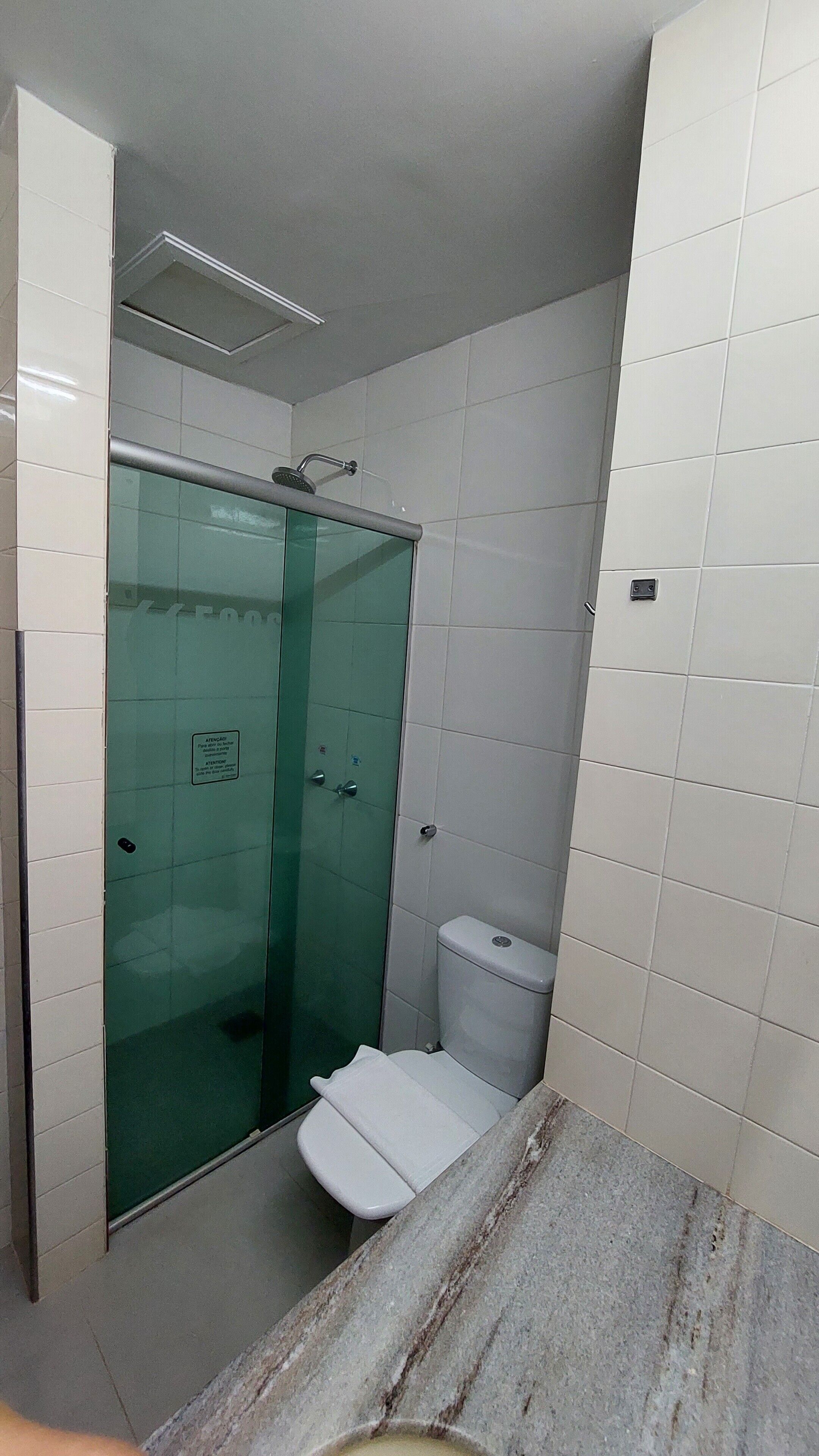 Un baño con cabina de ducha de vidrio, inodoro y encimera de mármol.