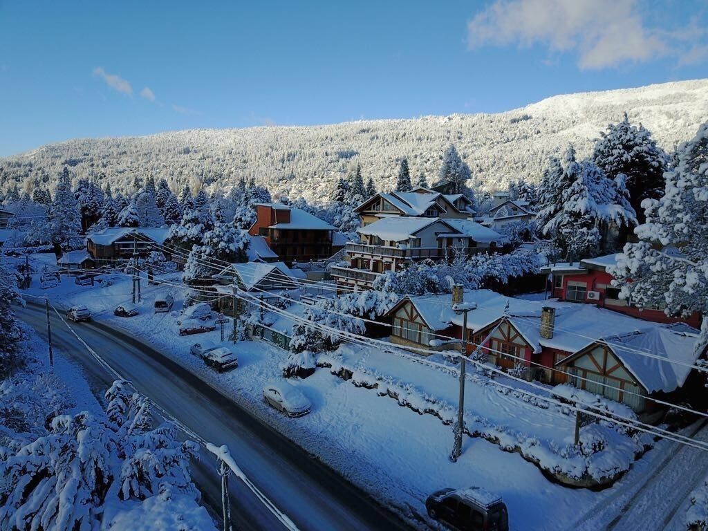Een besneeuwd dorp met traditionele houten huizen, een hoofdstraat en een berg op de achtergrond.