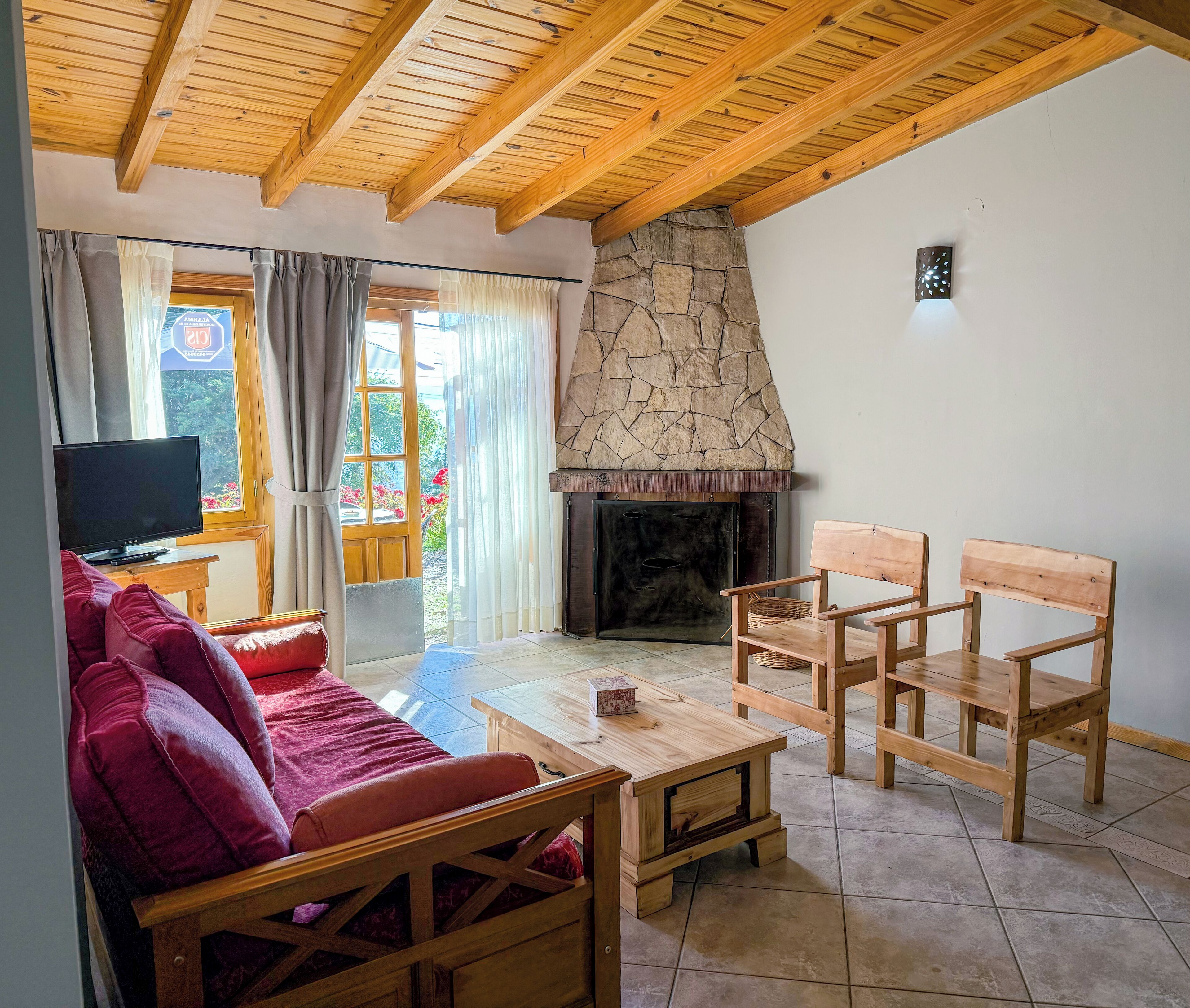 A cozy living room with a stone fireplace, wooden furniture, and a television.