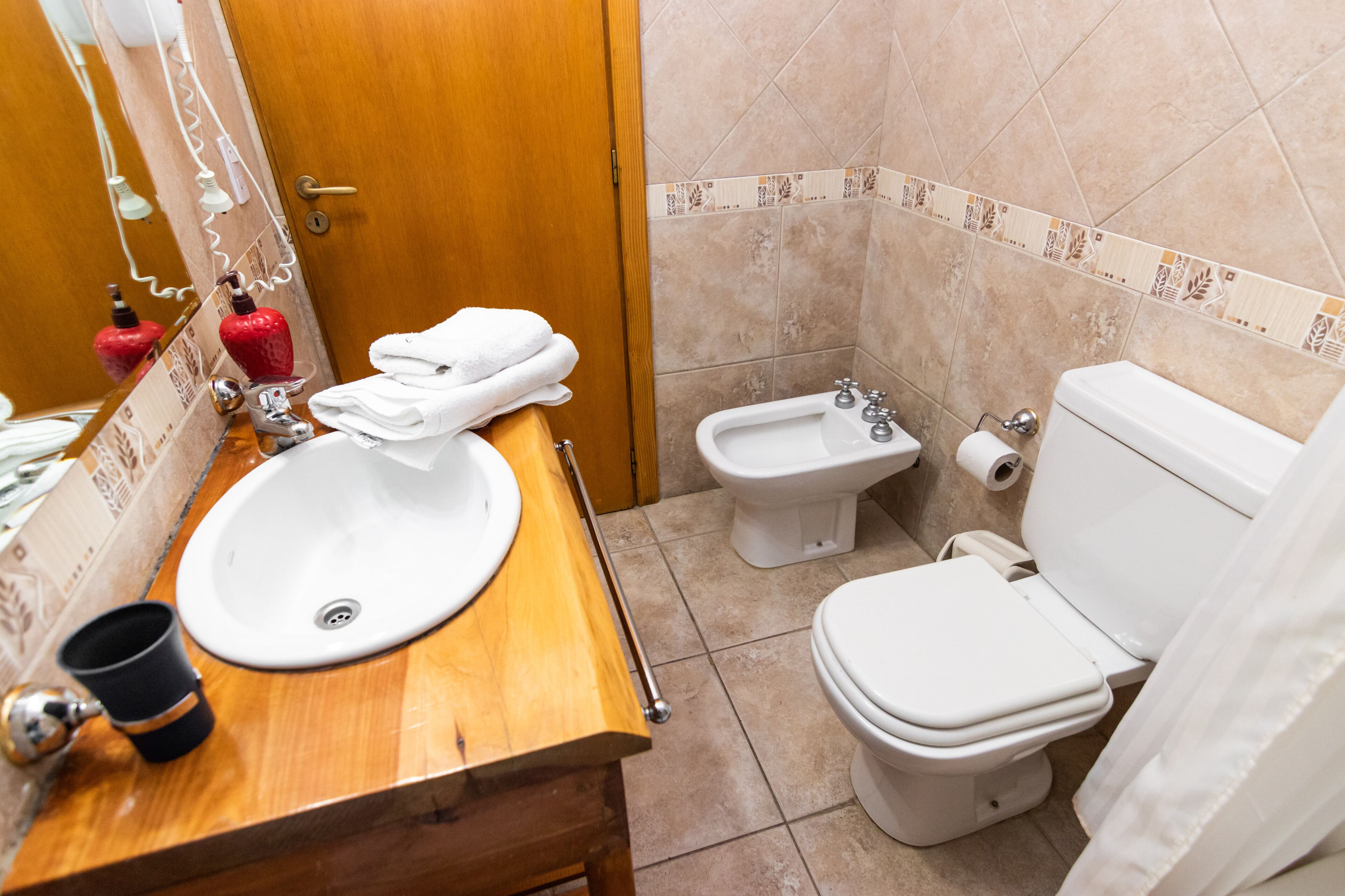 Un baño con tocador de madera, lavabo, bidé e inodoro.