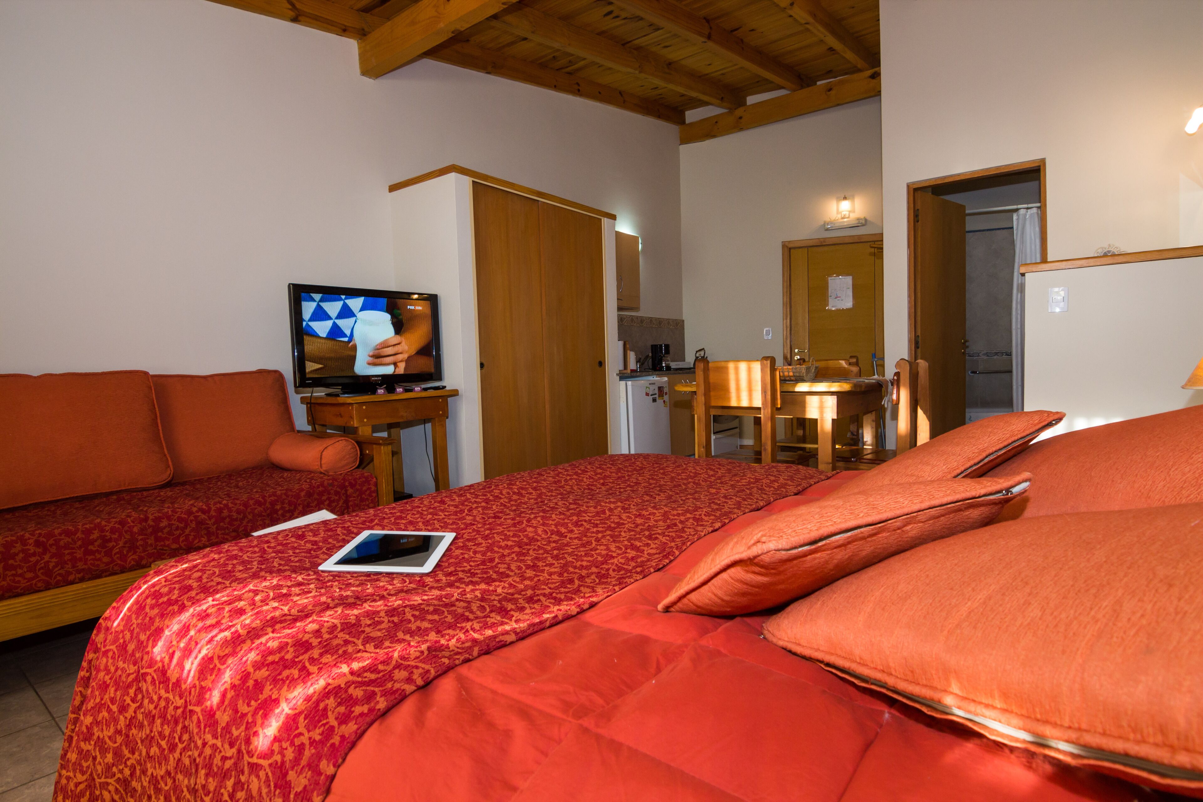 A hotel room with a large bed, a sofa, a television, and a desk.