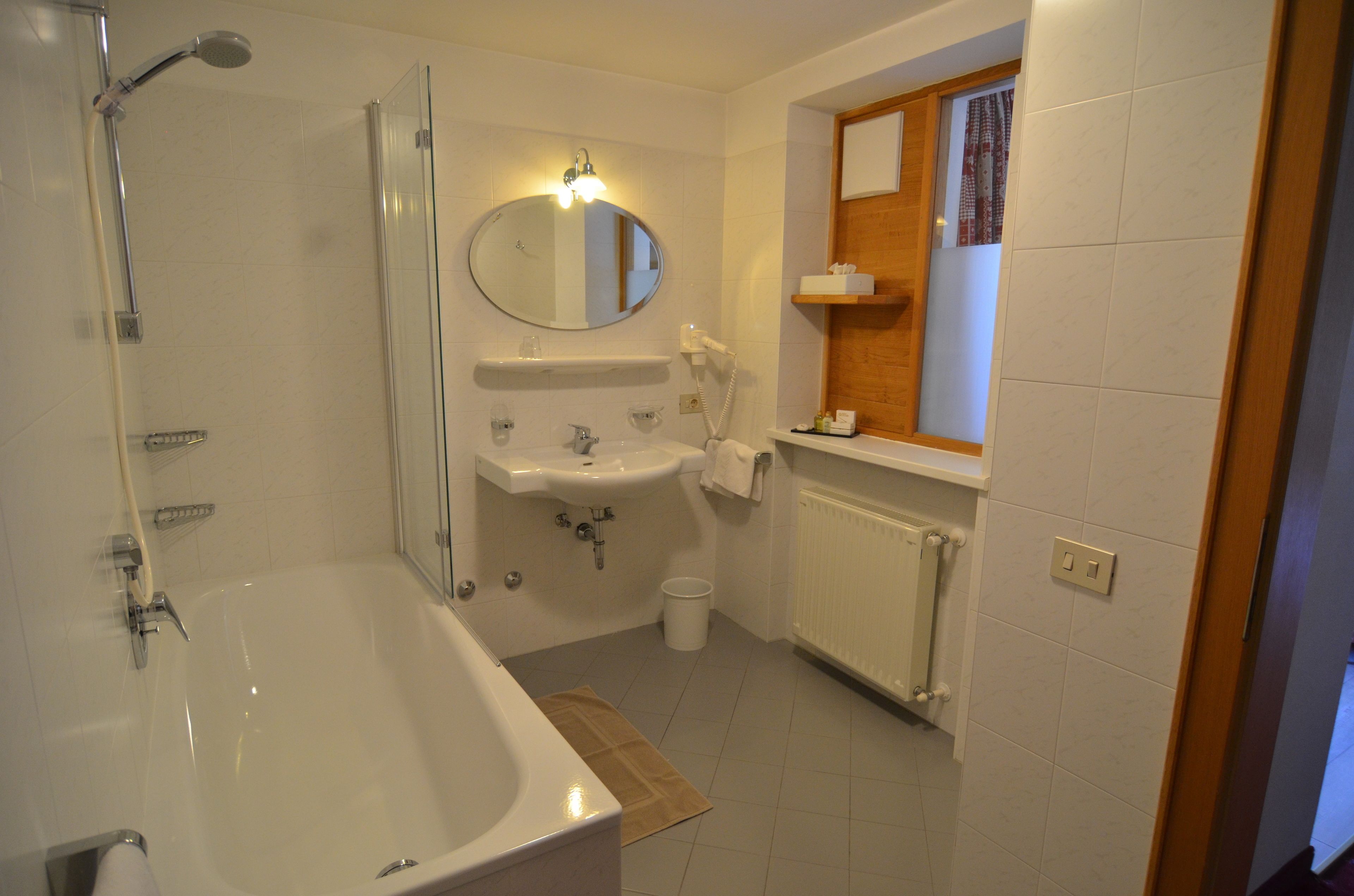A bathroom with a bathtub, a sink, a mirror, and a towel rack.