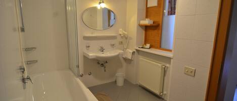 A bathroom with a bathtub, a sink, a mirror, and a towel rack.