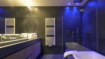 Un baño moderno con una bañera grande, una zona de ducha separada y un tocador con toallero.
