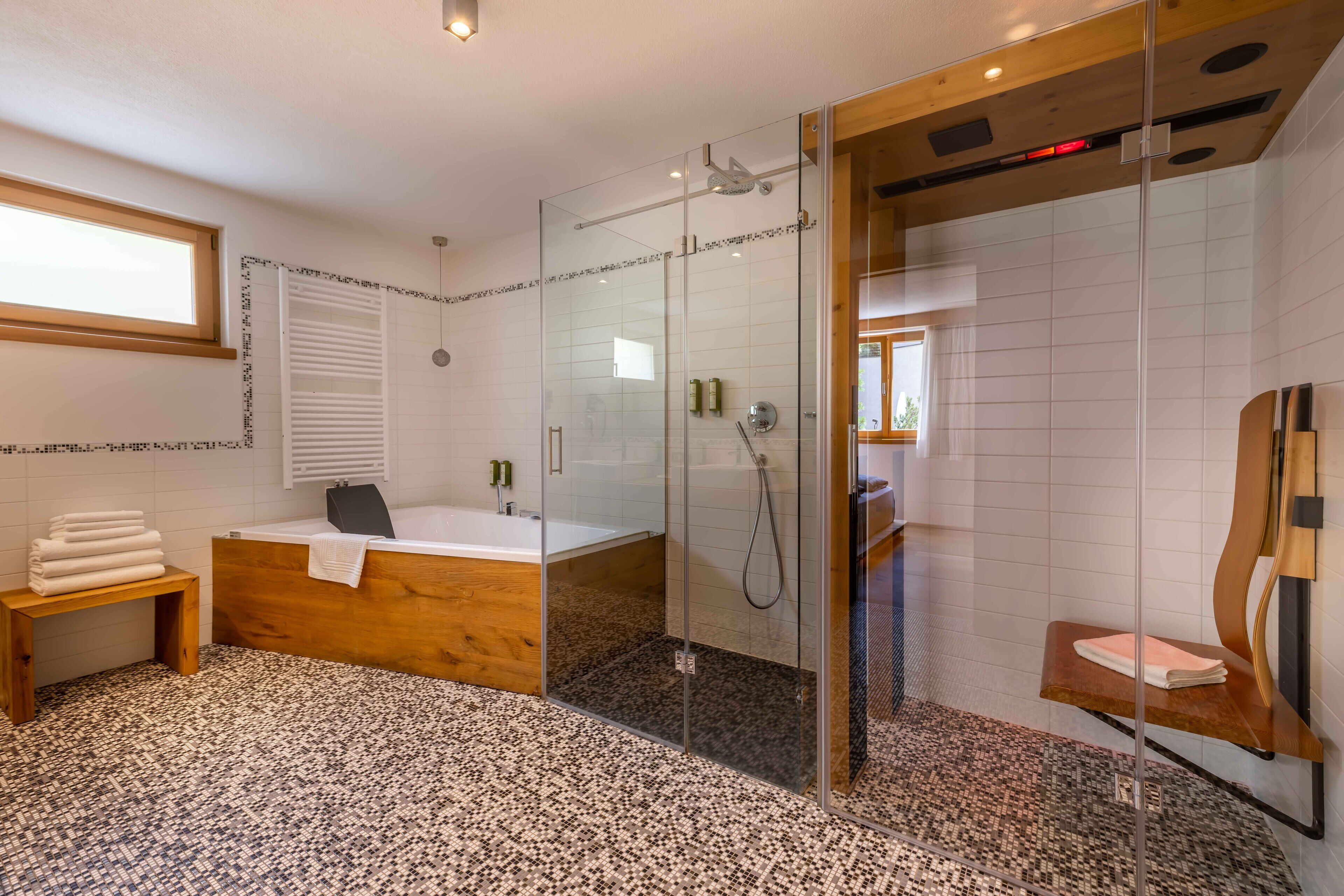 Un baño moderno con ducha envuelta en vidrio, una bañera independiente y un tocador de madera.