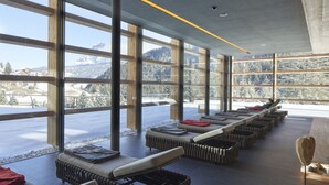 A modern interior with large windows offering mountain views, cushioned seating, and a minimalist design.