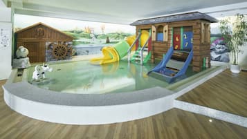 Enjoy a fun day at the pool with a playhouse, slides, and a ship wheel decoration.