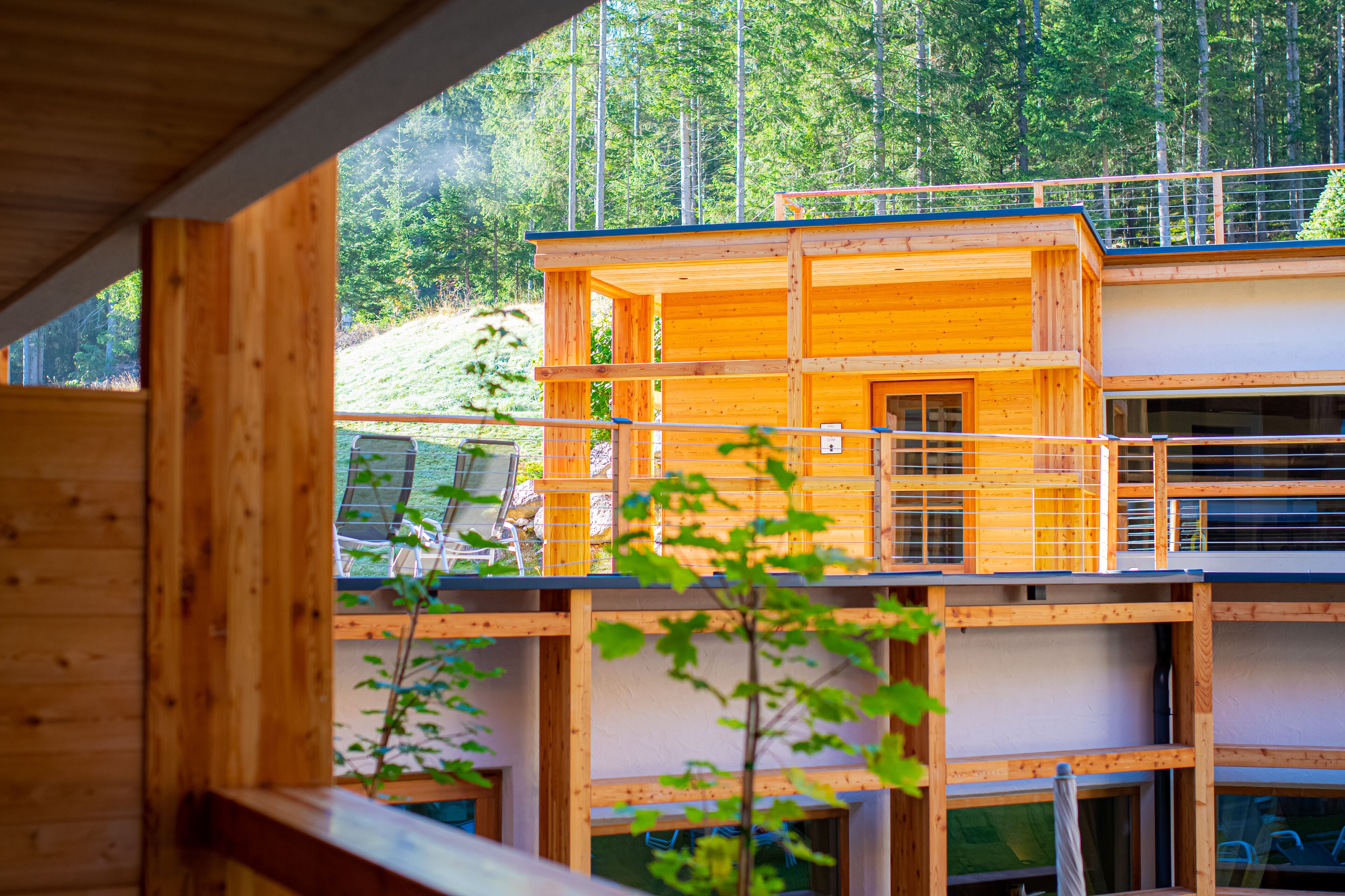 Una baita di legno a più piani con un balcone, immersa in una zona boschiva.