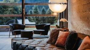 A modern living room with a leather sofa, round coffee table, and black chairs. A large, round, white pendant light hangs above the sofa.