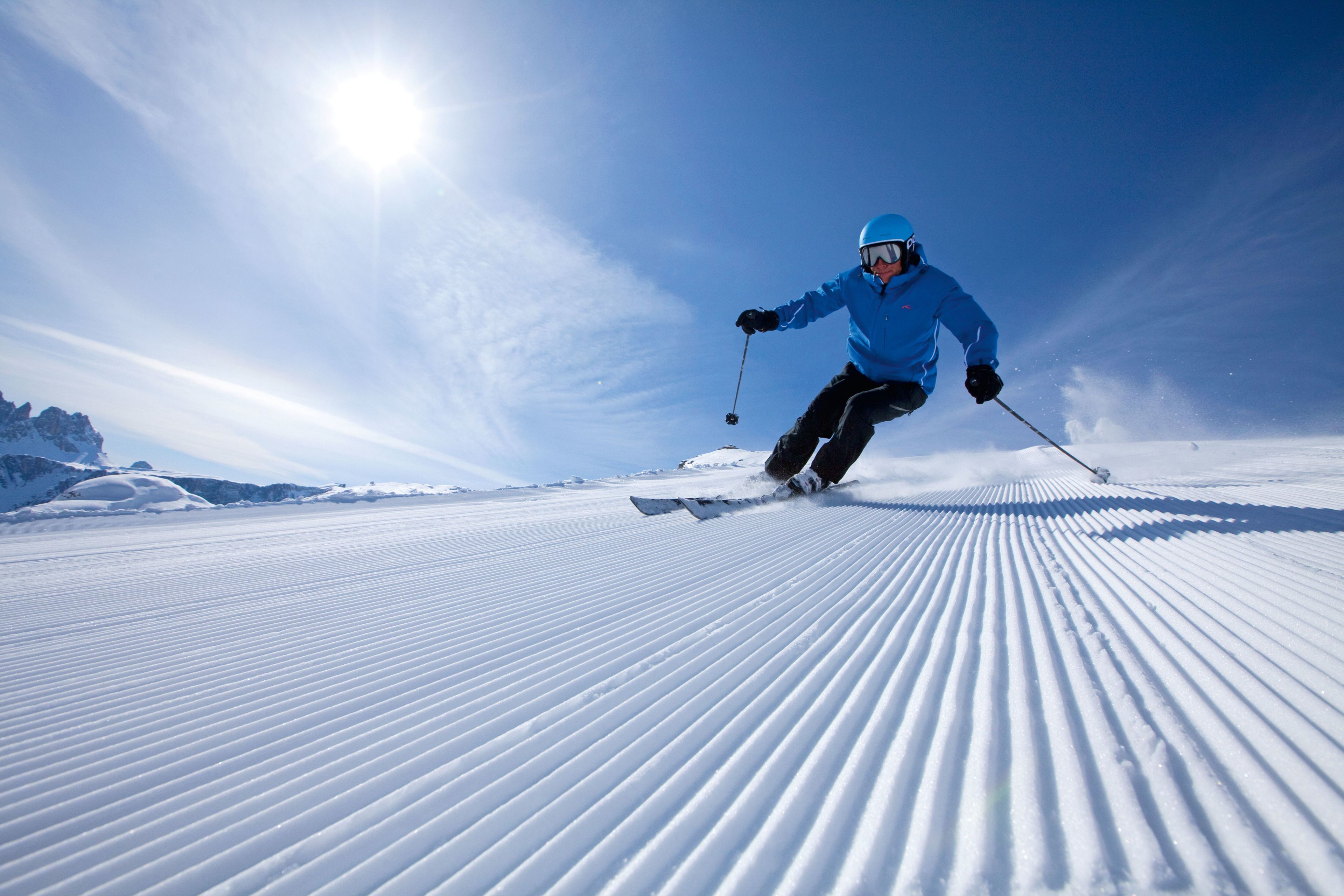 Een persoon skiënd op een met sneeuw bedekte helling onder een heldere lucht.