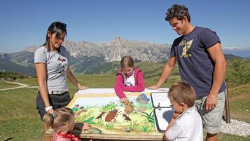 Una familia junto a una mesa con un expositor educativo de temática natural, con montañas al fondo.