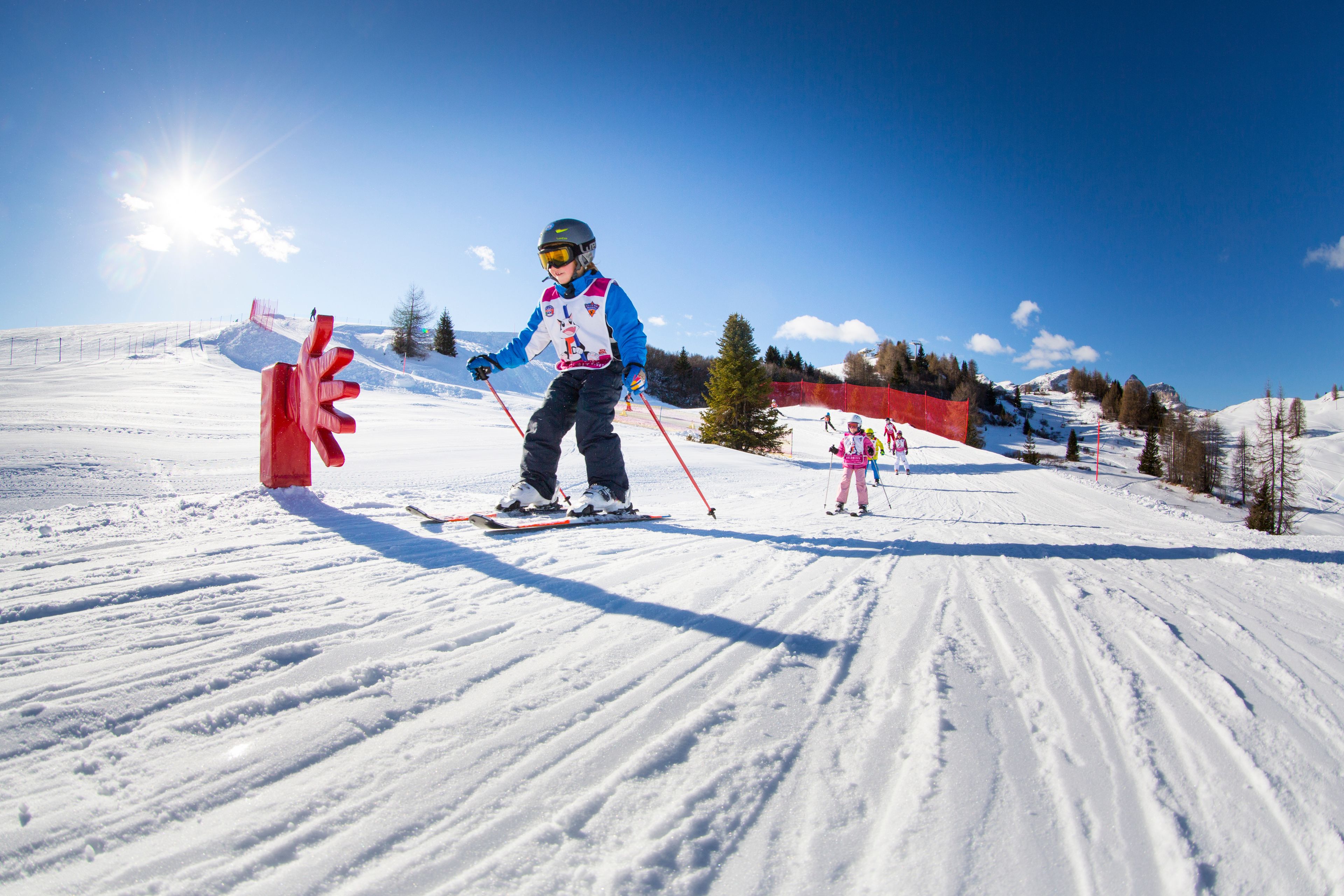 A ski slope with a skier and a child.