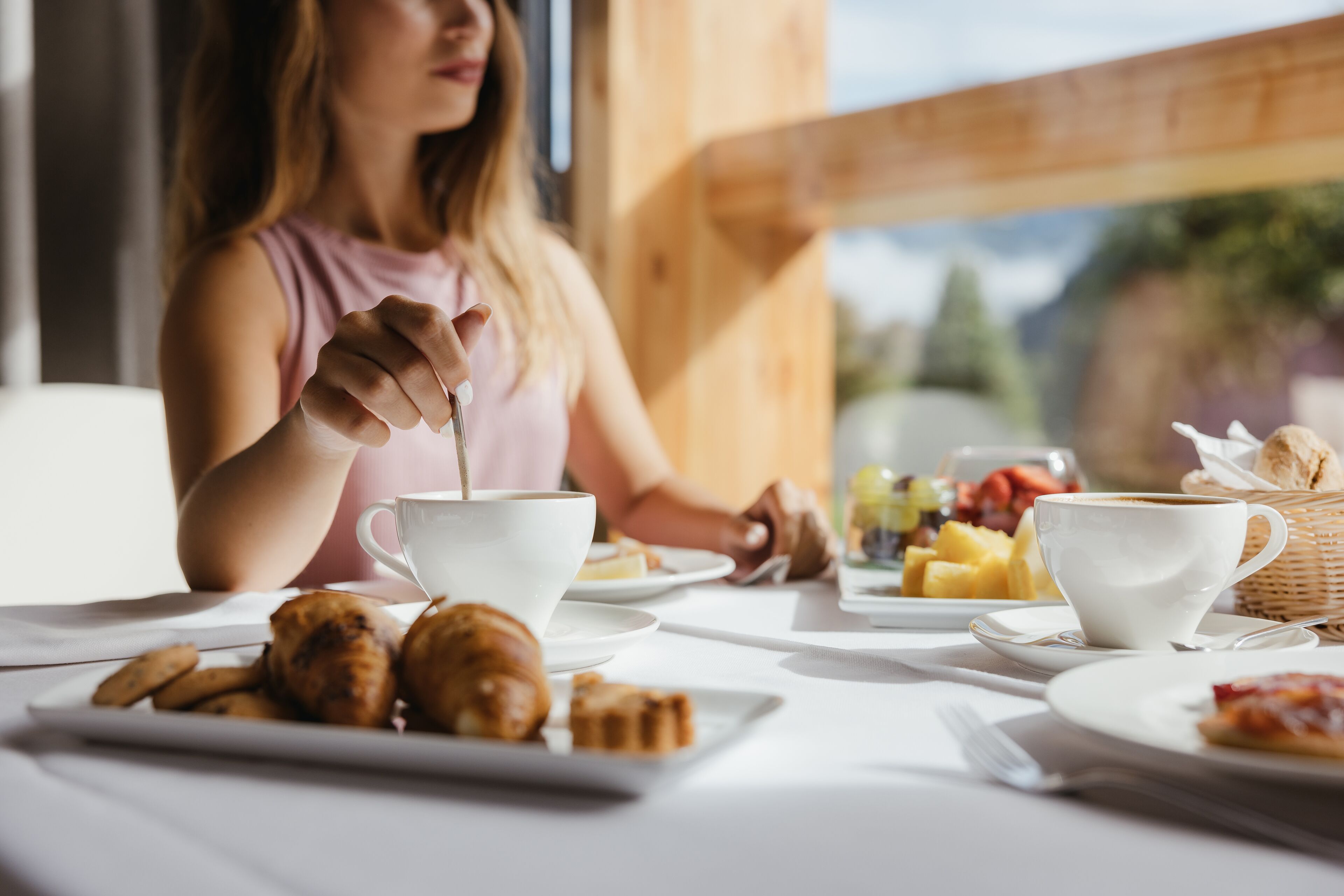 A breakfast setting with a table, cups, pastries, and fruit.
