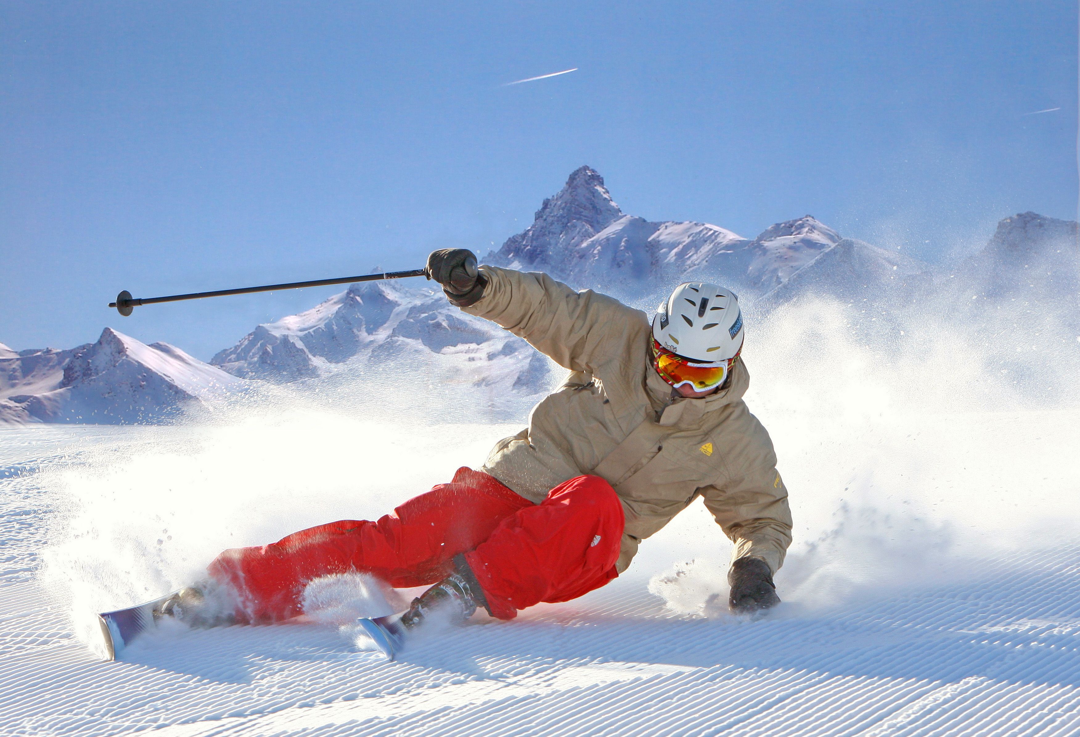 A person skiing on a snowy slope with mountains in the background.