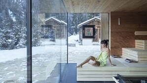 A spa area with a large glass window, wooden deck, and a wooden cabin visible outside.
