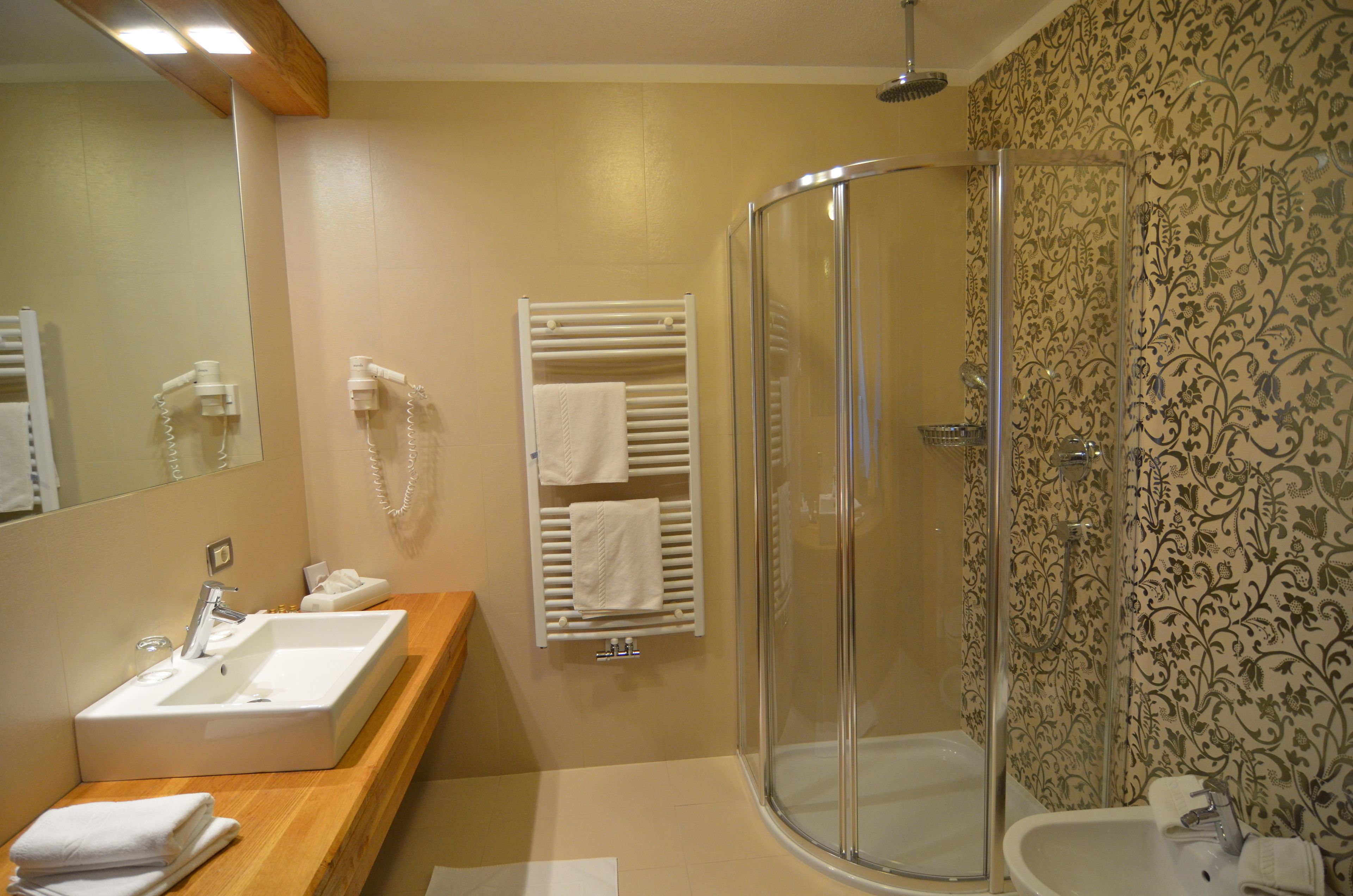 A bathroom with a wooden vanity, a glass shower enclosure, and a patterned wall.