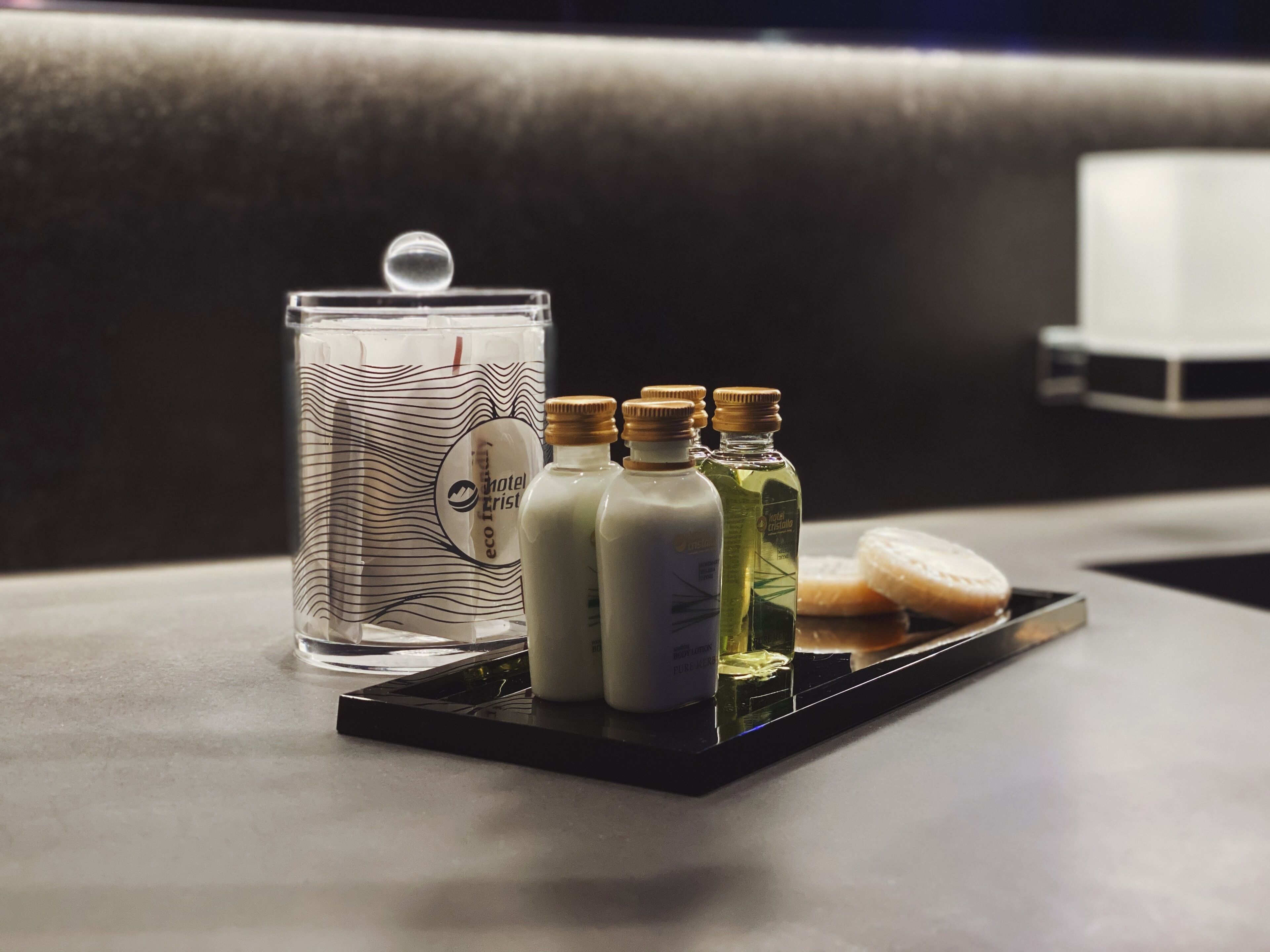 A tray with a glass container, three bottles, and a bar of soap on a table.