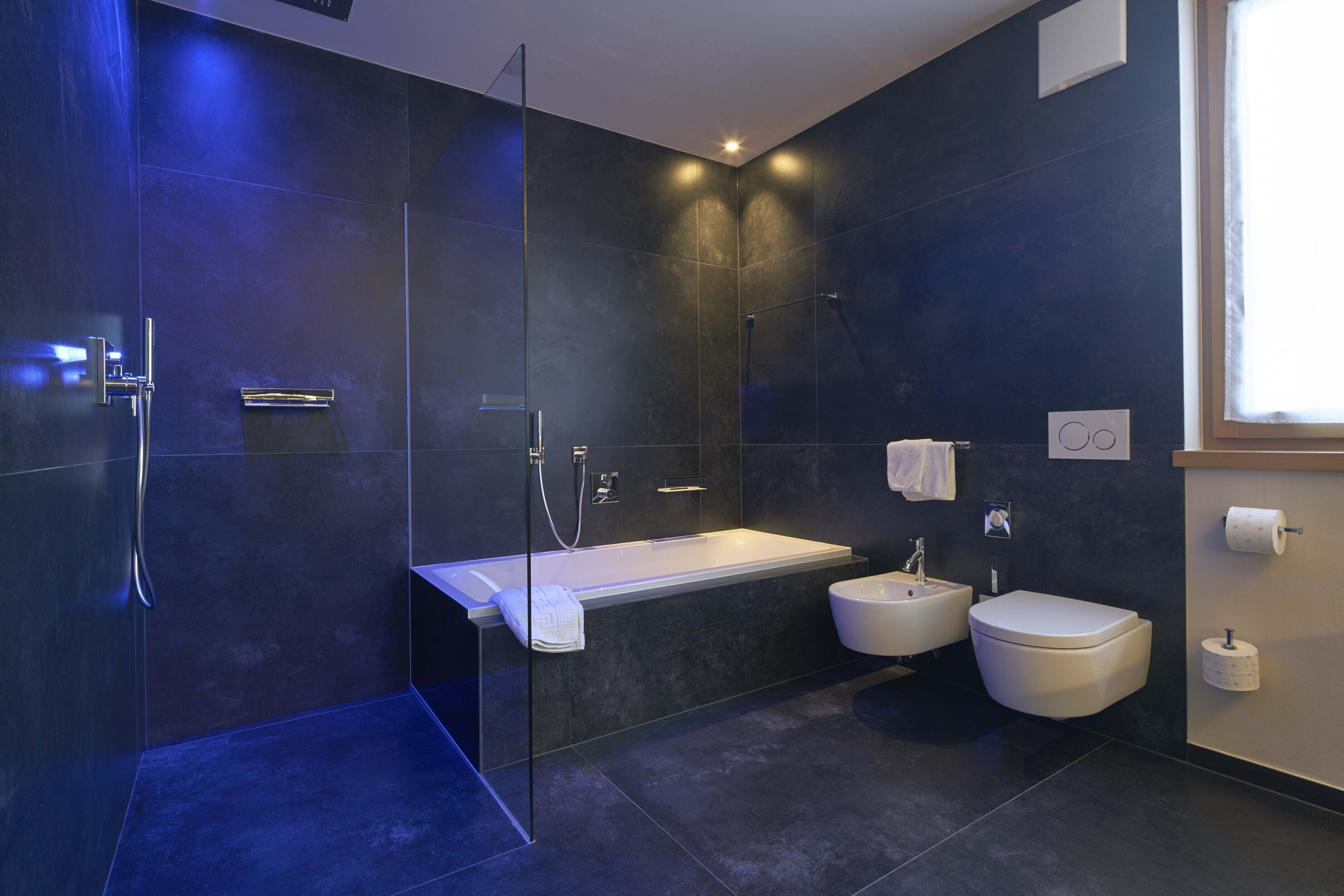A modern bathroom with a glass-enclosed shower, a freestanding bathtub, a sink, and a toilet.