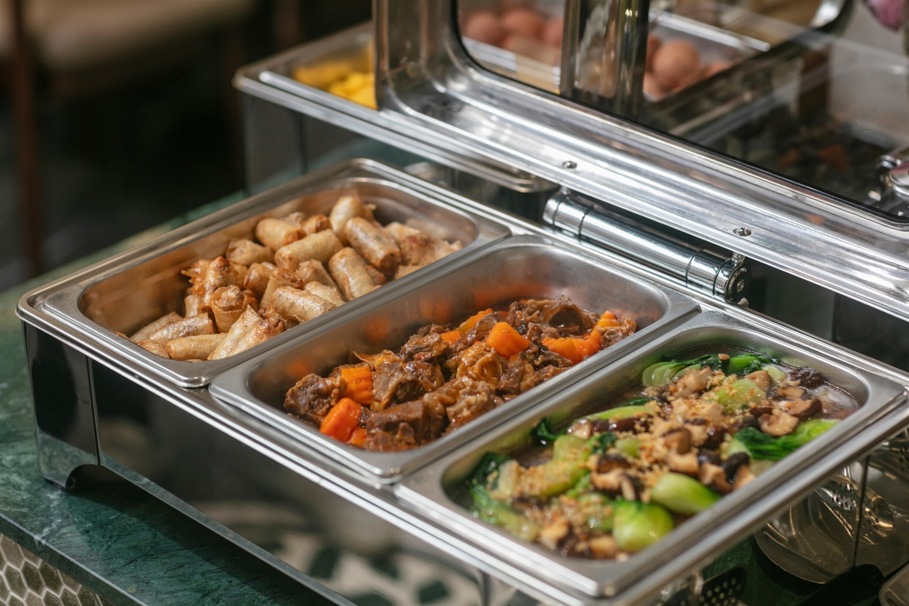 A buffet with various food options including sausages, beef stew, and vegetables.