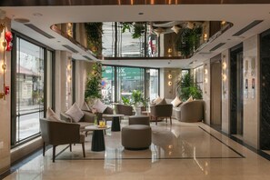 A spacious lobby with a high ceiling, modern furniture, and large windows offering a view of the street. - Hong Ngoc Cochinchine Boutique Hotel & Spa (Hanoi)