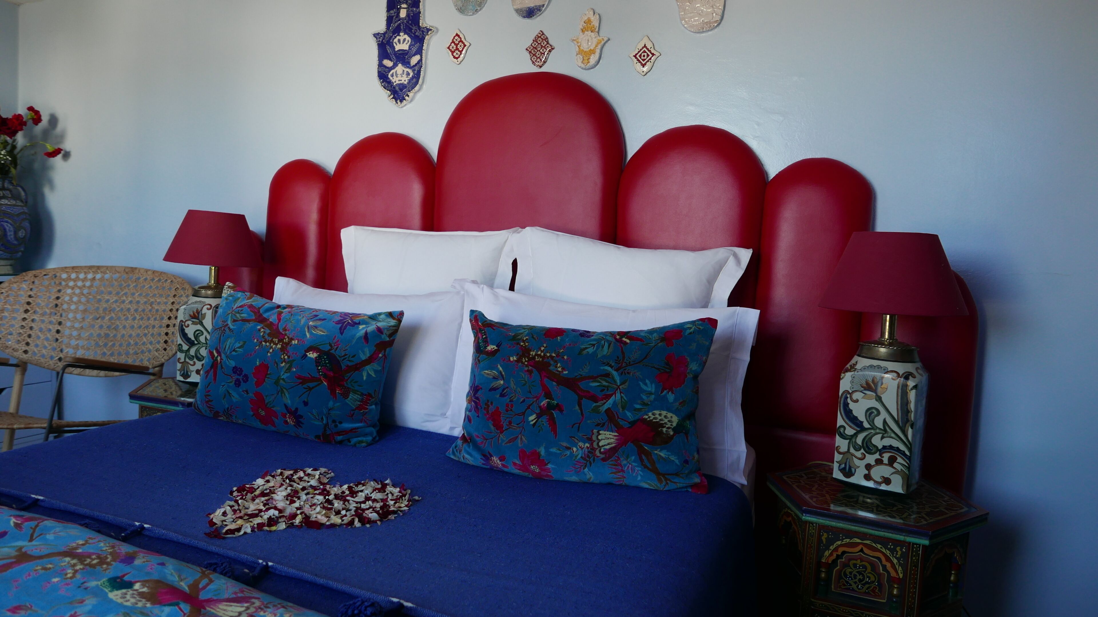 A bed with a red headboard, white pillows, and blue floral bedspread.