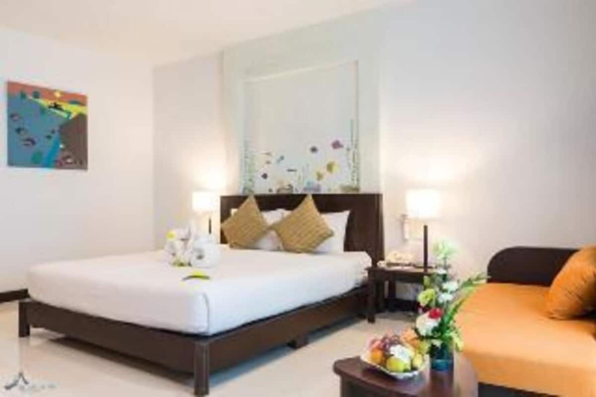Ein Hotelzimmer mit Bett, Nachttisch, Lampe und einem kleinen Tisch mit Blumen.