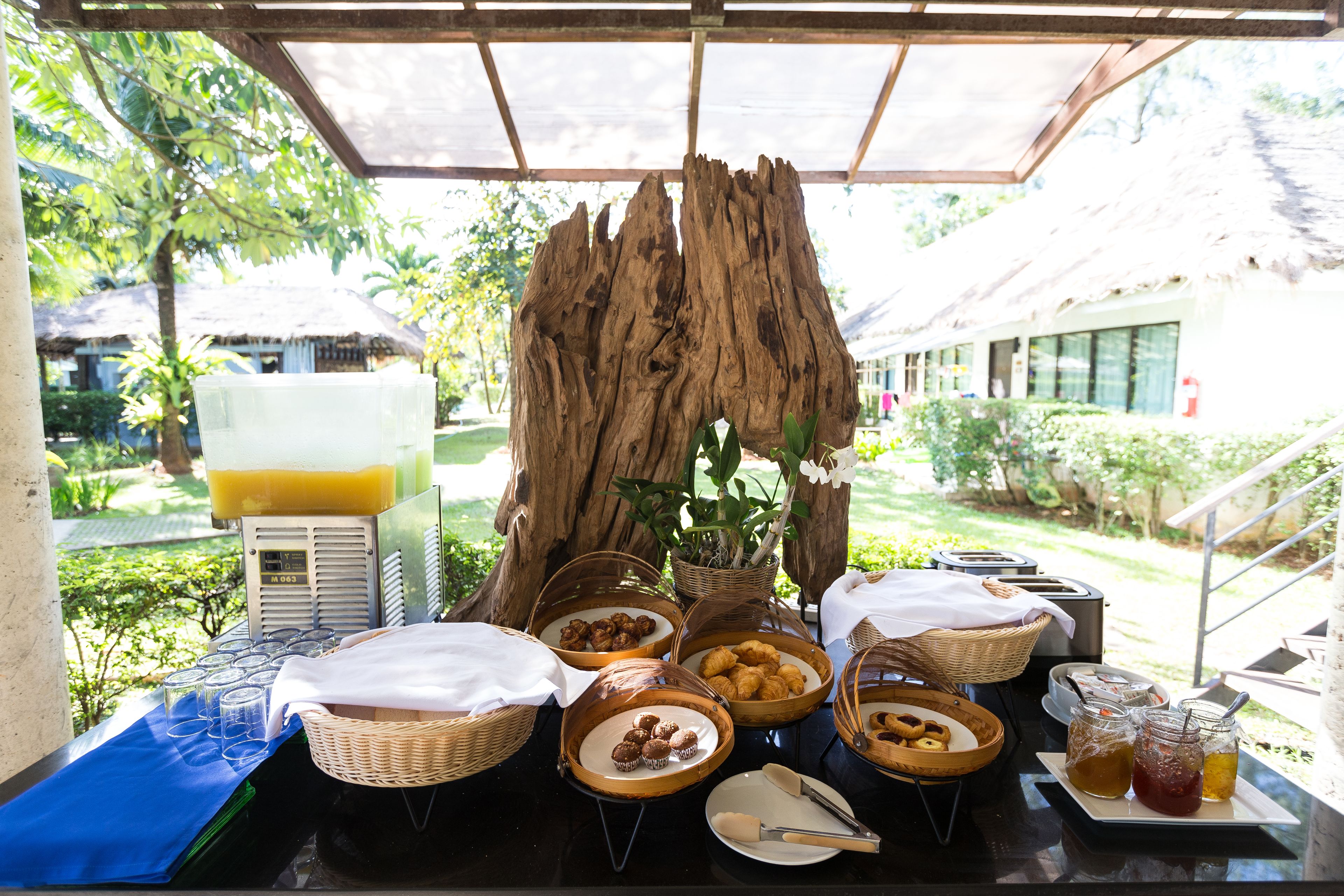 Un bufé de desayuno con diferentes opciones de comida y un dispensador de zumo.