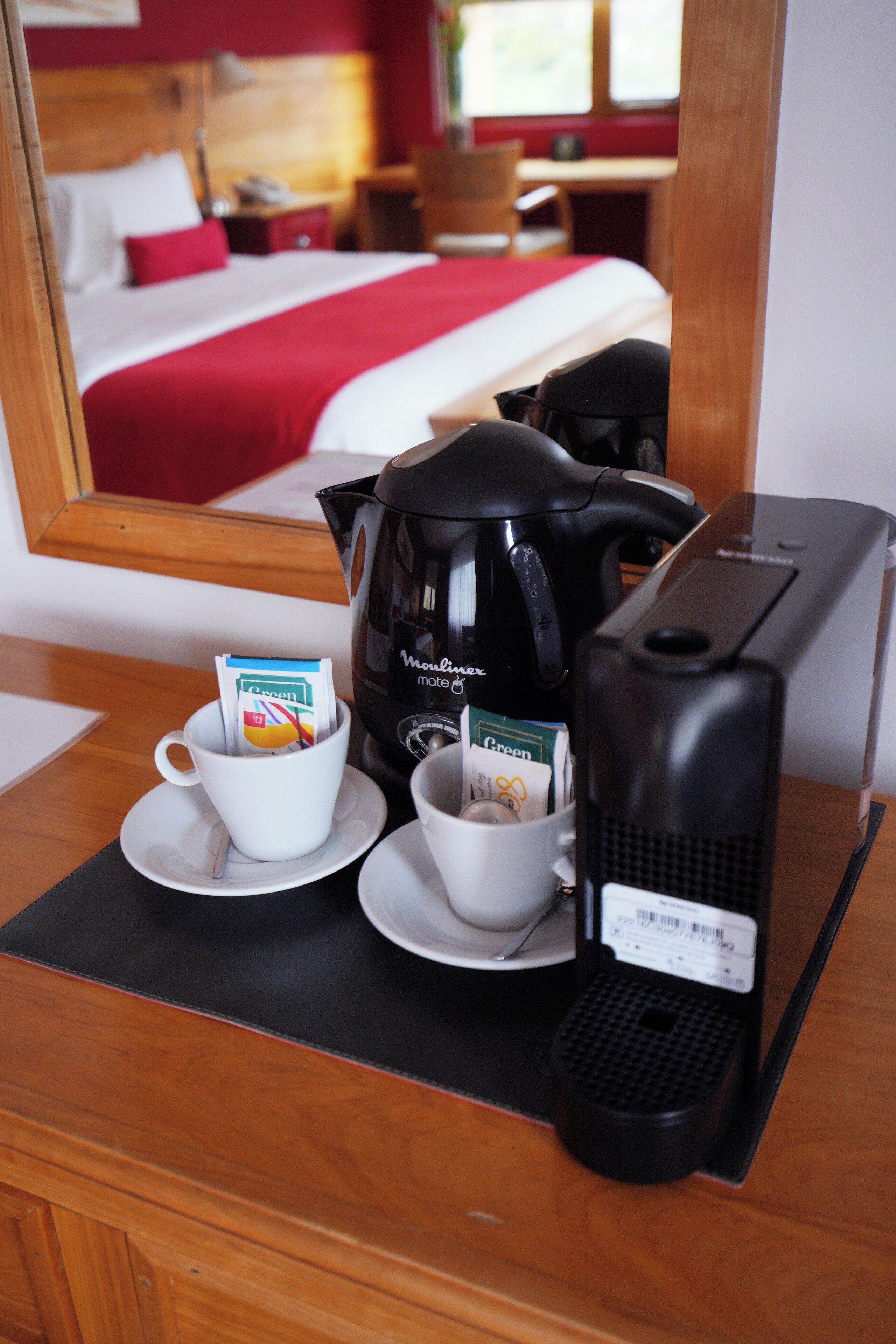 A hotel room with a bed, a coffee maker, and a cup of coffee on the table.