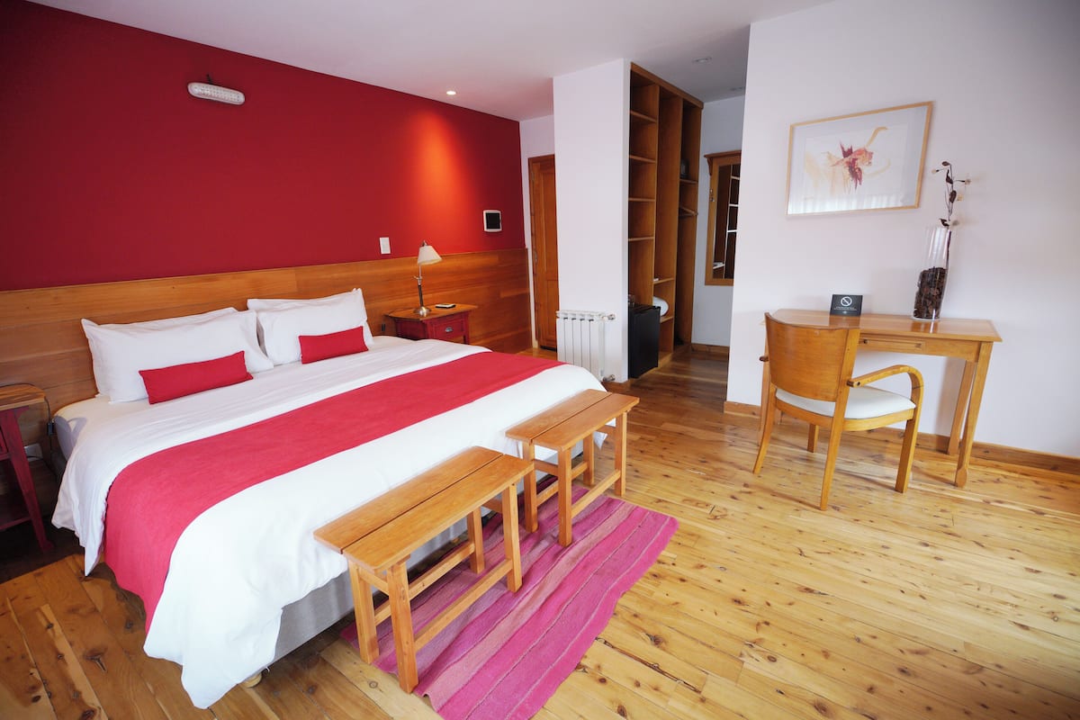 A bedroom with a wooden bed, a desk, and a chair.
